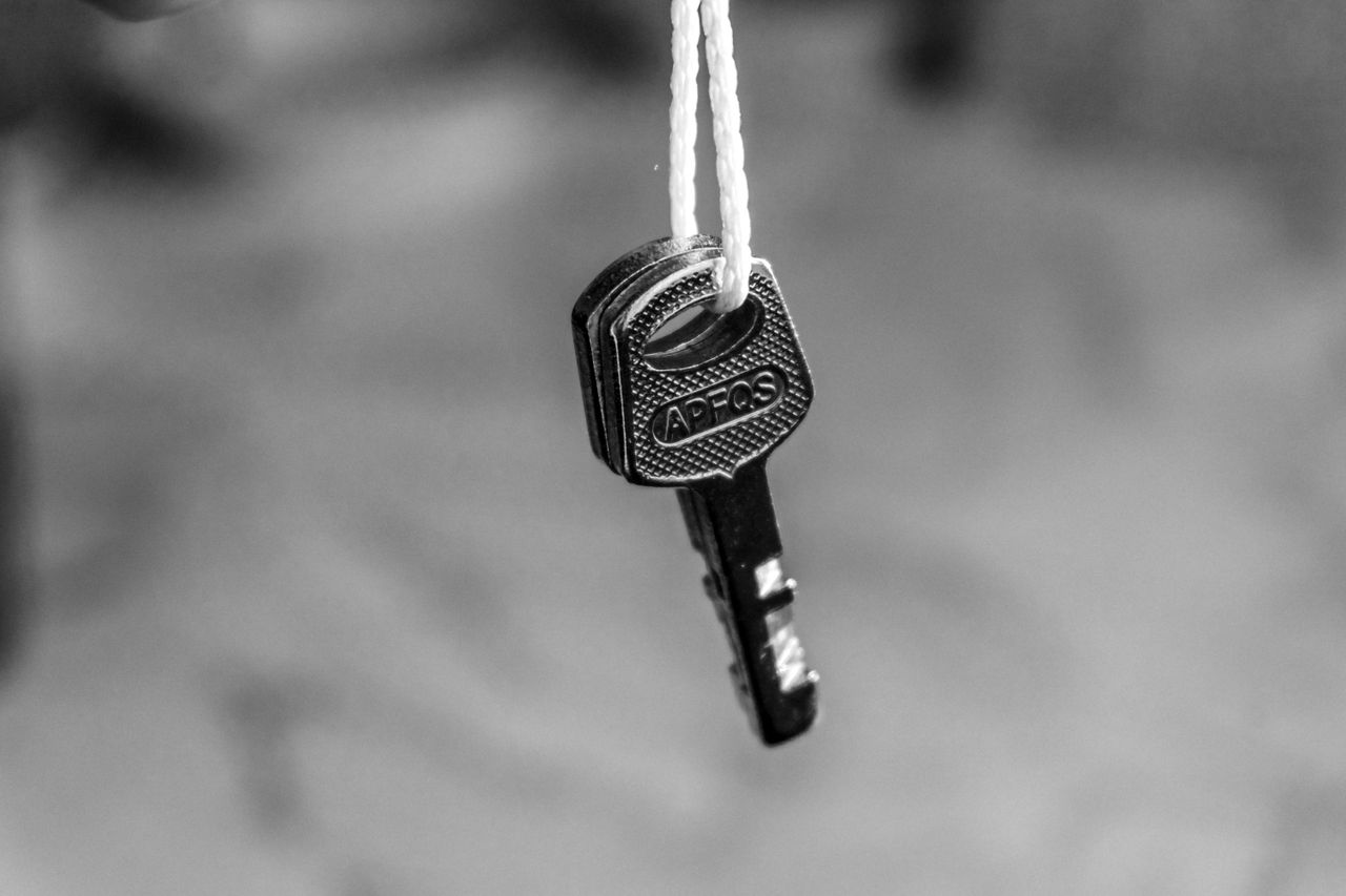 Monochrome image of a key hanging on a string, emphasizing security concepts.